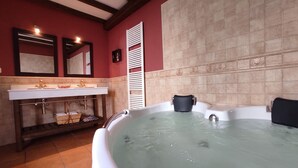 A bathroom with a bathtub, a sink, and a mirror. - Ländliches Haus mit Jacuzzi by Interhome (Valor)