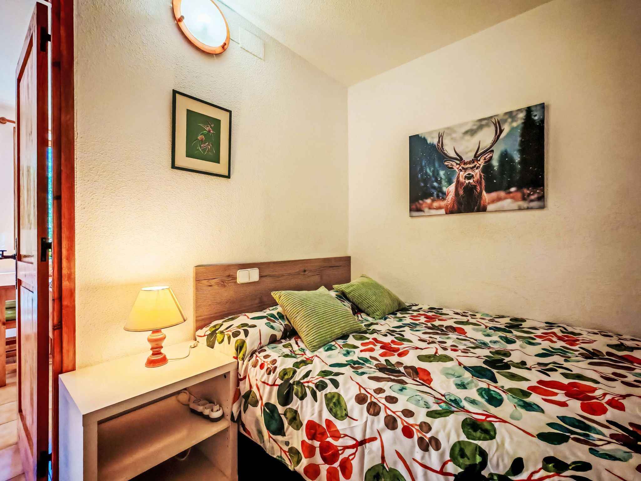 Ein Schlafzimmer mit einem Bett, einem Nachttisch, einer Lampe, einem gerahmten Bild und einem Gemälde an der Wand.