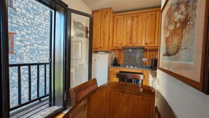 Une cuisine avec des meubles de rangement en bois, un plan de travail en granit, un réfrigérateur et une table à manger avec des chaises.