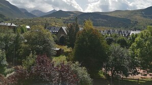 Un paysage montagneux avec un village, des bâtiments en pierre et une végétation luxuriante.