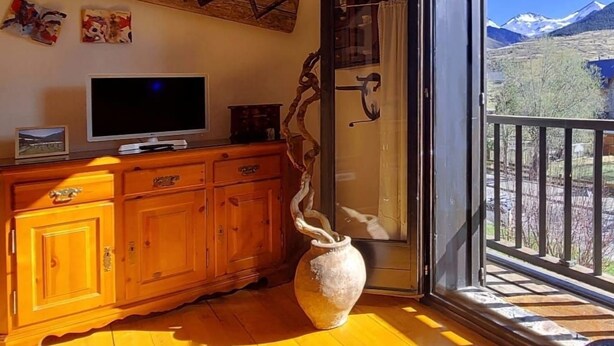 Une pièce avec un meuble en bois, une télévision et un vase.