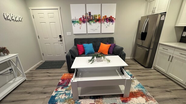 Eine moderne Küche mit grauem Sofa, bunten Kissen, einem weißen Couchtisch und einem lebendigen Teppich.