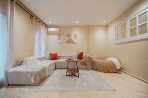 Ein modernes Wohnzimmer mit einer Eckcouch, einem runden Couchtisch und einem großen Fenster mit Vorhängen.