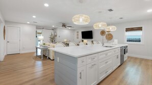 A spacious kitchen with a large island, white cabinetry, and pendant lighting. - Seashellin' - Short walk to beach (Panama City Beach)