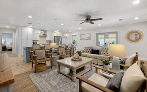 A spacious living room with a sofa, chairs, a coffee table, and a dining area.