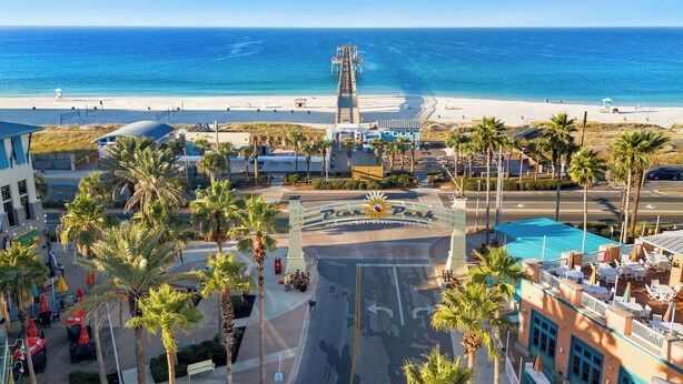 A beachside resort with a prominent pier, palm trees, and a clear view of the ocean. - Seashellin' - Short walk to beach (Panama City Beach)