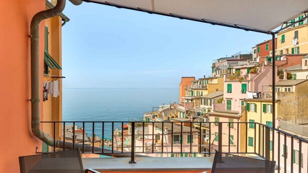 A balcony with a view of the sea and colorful buildings. - Splendid Holiday Home in the Heart of Riomaggiore with Sea View TerraceLocated in the historic center of Riomaggiore, a few steps from the station and the best restaurants and bars in the village, this holiday home is the ideal choice for those who want  (Riomaggiore)