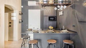 A modern kitchen with a central island, bar stools, and a hanging pot rack. - Splendid Holiday Home in the Heart of Riomaggiore with Sea View TerraceLocated in the historic center of Riomaggiore, a few steps from the station and the best restaurants and bars in the village, this holiday home is the ideal choice for those who want  (Riomaggiore)