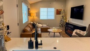 Ein Wohnzimmer mit Kamin, Weihnachtstannenbaum, Sofa und Fernseher.
