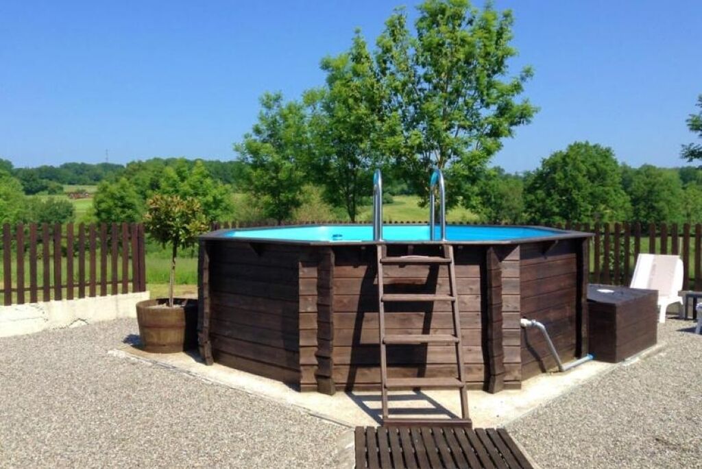 A wooden pool structure with a ladder, a small tree, and a bench.