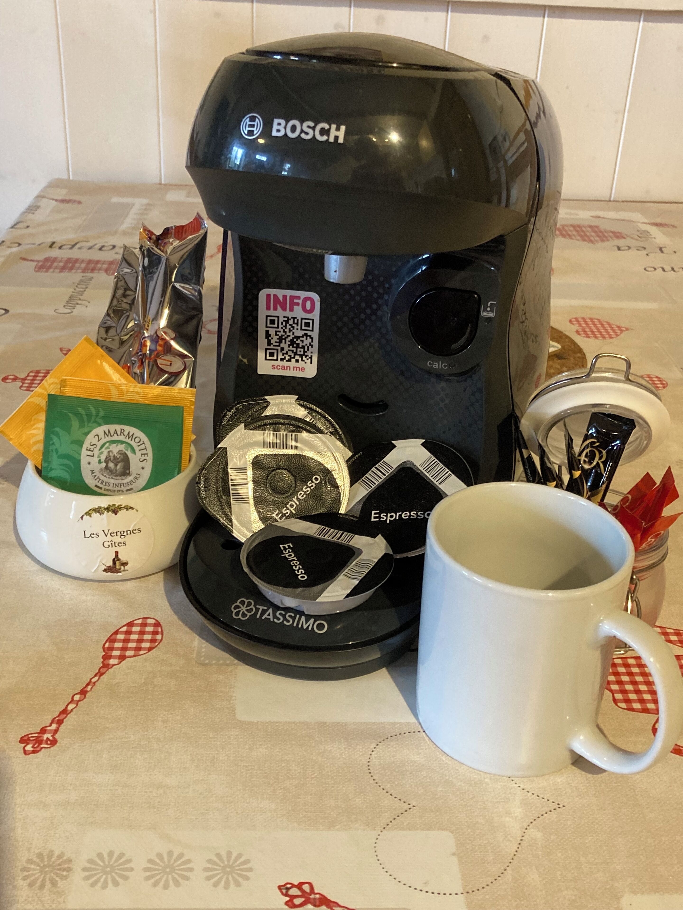 A coffee maker, a mug, and coffee pods on a table.