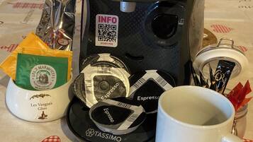 A coffee maker, a mug, and coffee pods on a table.