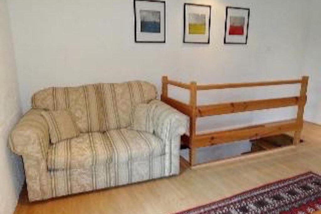 Une pièce avec un canapé et un banc en bois, le tout adossé à un mur blanc.