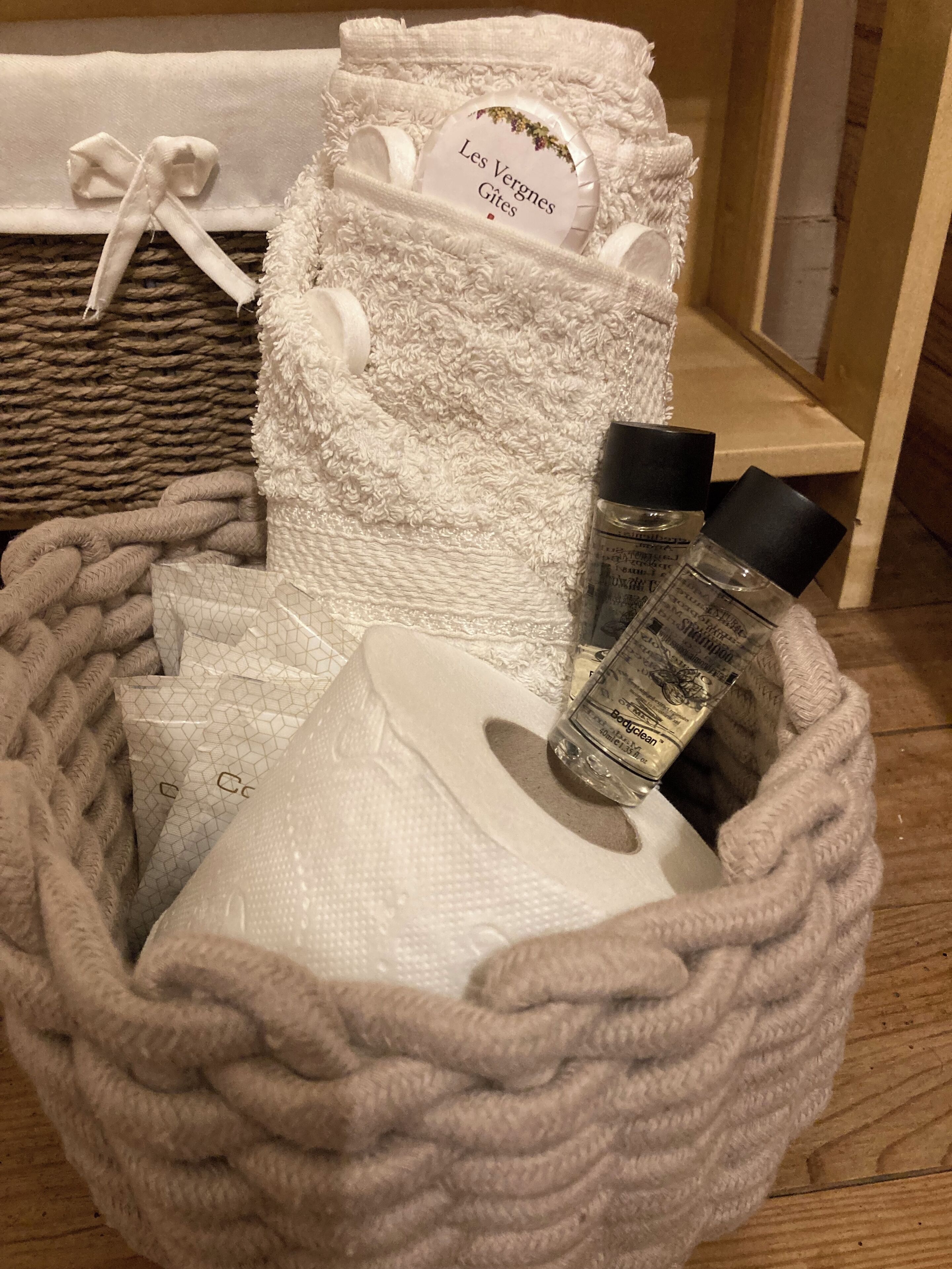 A basket containing toiletries, including a bottle of body clean and a white towel with a label.