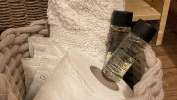 A basket containing toiletries, including a bottle of body clean and a white towel with a label.