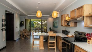 Una cocina moderna con armarios de madera, una isla central con taburetes altos e iluminación colgante.