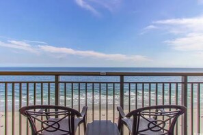 Ein Balkon mit zwei Stühlen mit Blick auf einen Strand.