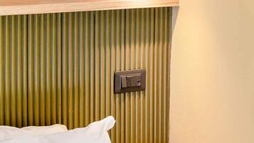A room with a textured wall, a wooden shelf, and a power outlet.