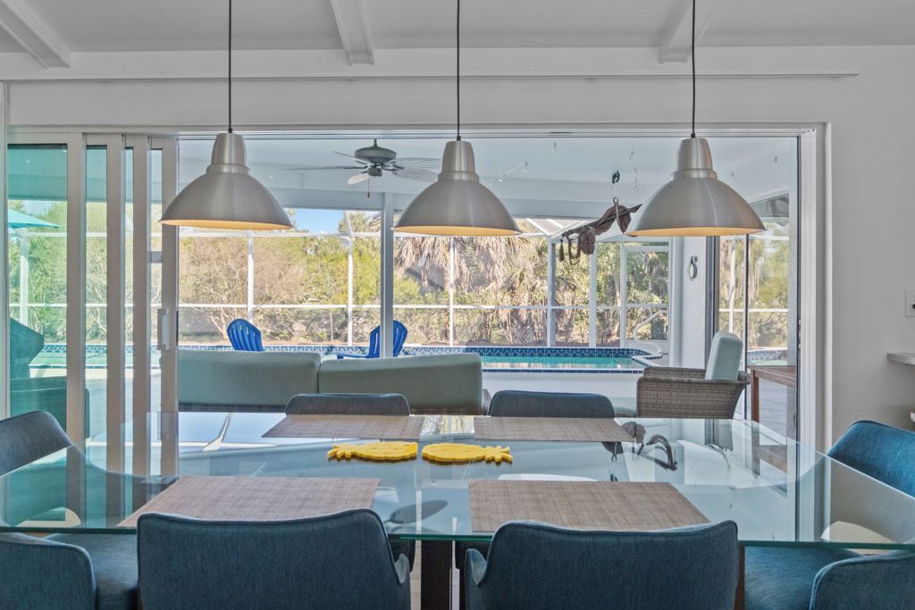 A modern dining area with a glass table, blue chairs, and pendant lights.