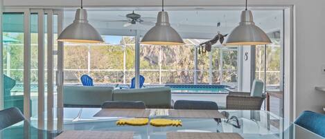 A modern dining area with a glass table, blue chairs, and pendant lights.