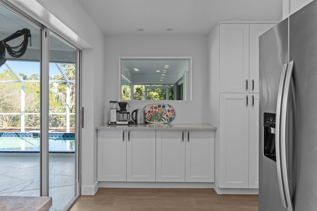 Eine moderne Küche mit weißen Schränken, einem Edelstahlkühlschrank und einer Kaffeemaschine.