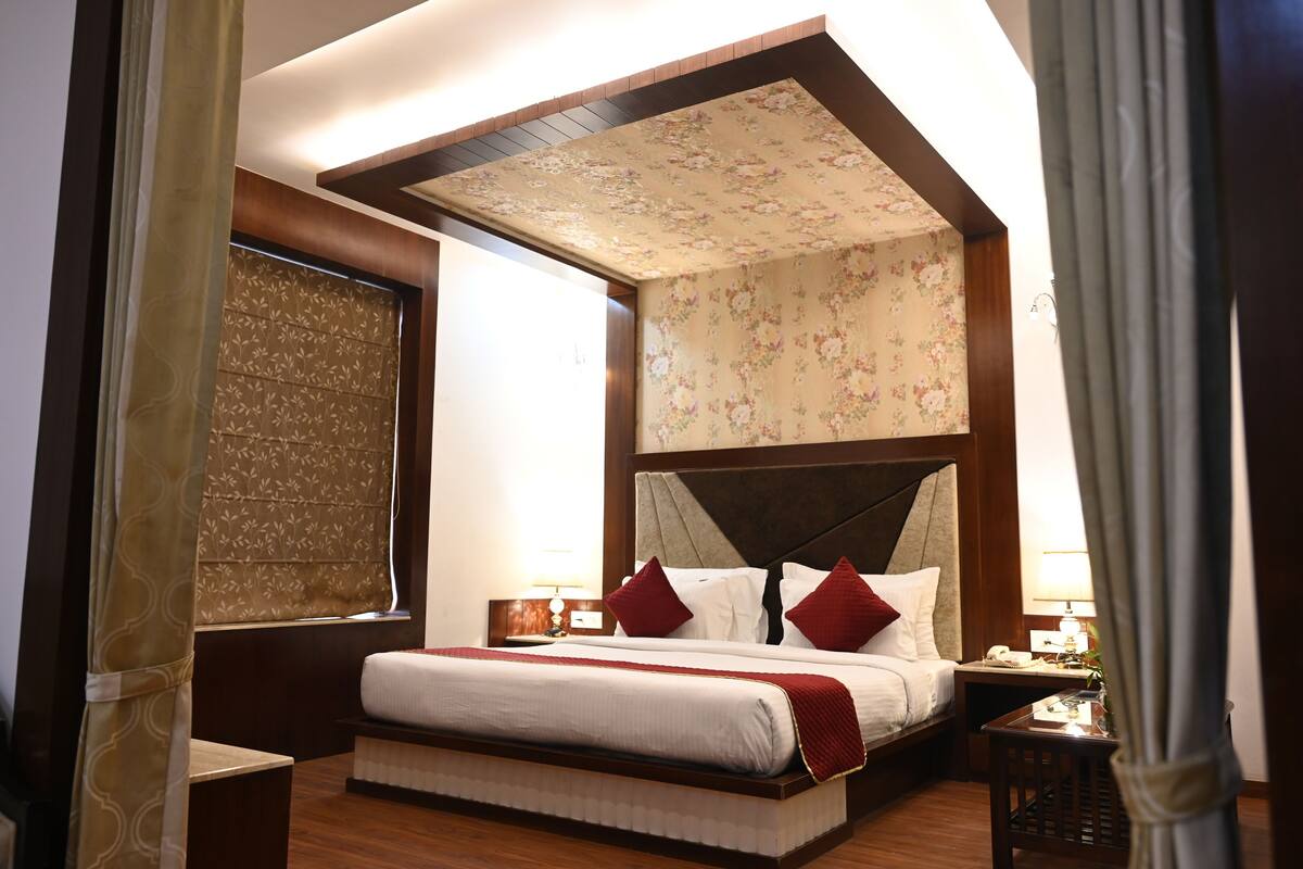A hotel room with a large bed, floral wallpaper, and a wooden ceiling.