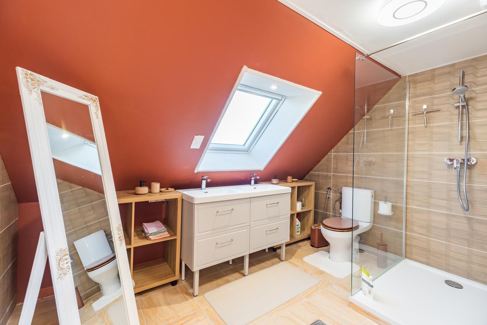 A modern bathroom with a skylight, a glass shower enclosure, and a vanity with storage.
