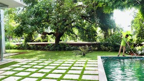 A swimming pool with a tiled deck and a lush garden in the background. - A 3BHK Luxury Villa with Pvt Pool, Garden Near Beach (Siolim Goa)