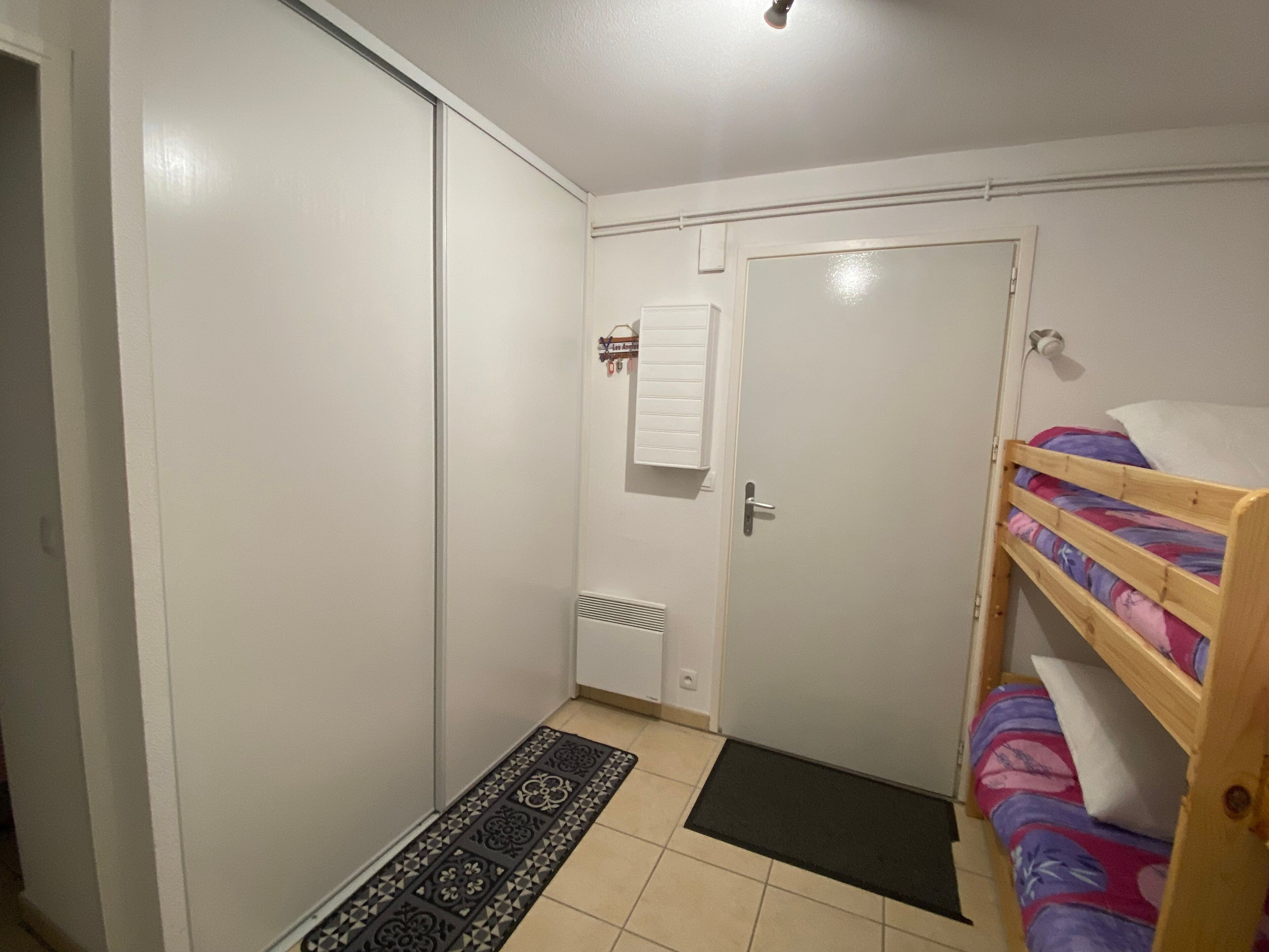 A small, clean room with a bunk bed, a door, and a radiator.