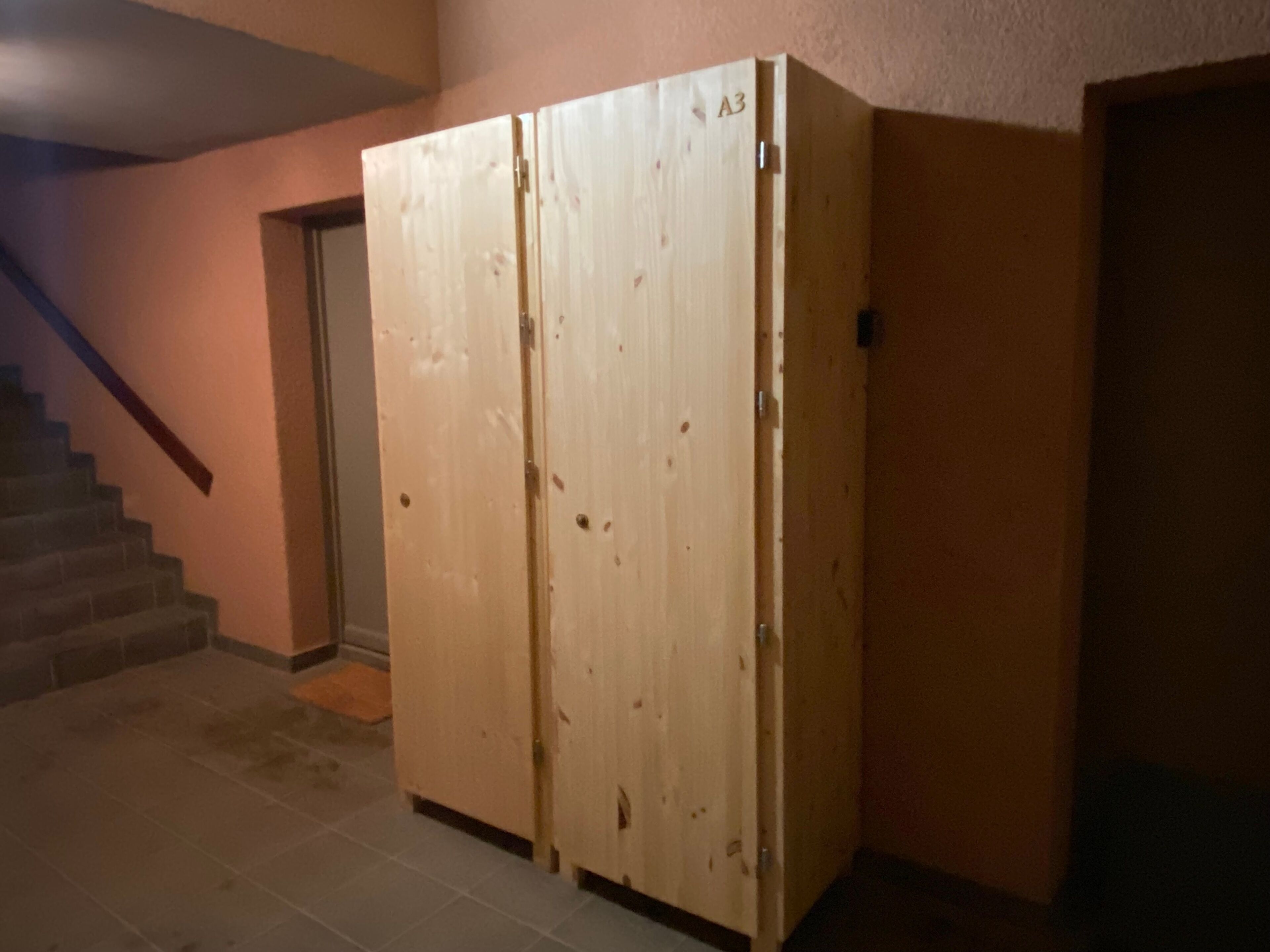 Un meuble en bois avec une porte, un escalier et un mur.