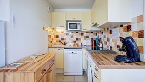 A compact kitchen with a microwave, dishwasher, and coffee maker. - Le Balcon du Lac - Navette devant résidence (Les Angles)