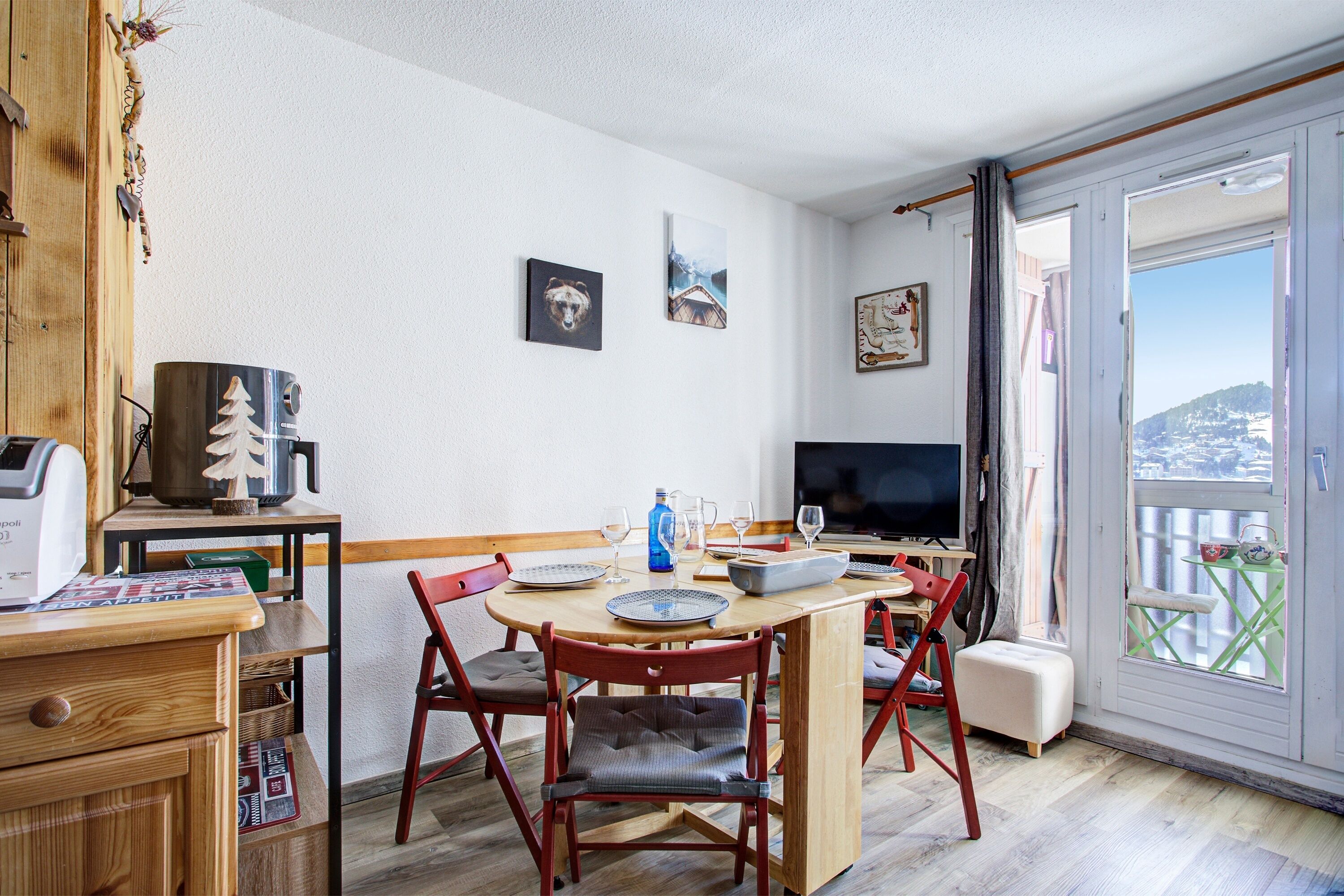 Un comedor con una mesa de madera, sillas y un televisor.