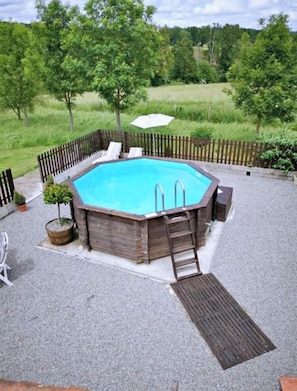 A rectangular swimming pool with a wooden deck, surrounded by a wooden fence, and a ladder leading into the pool. - Cogulet Gite de caractere avec piscine - 2 bedrooms -campagne Charantaise (Exideuil-sur-Vienne)