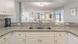 A modern kitchen with white cabinets, a granite countertop, and a stainless steel sink. - Spacious 3-bedroom condo at Grande Shores inn serene Myrtle Beach (Myrtle Beach)