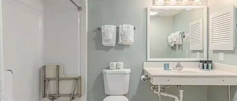 A bathroom with a toilet, sink, and shower area.
