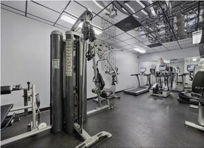 Ein Fitnessstudio mit verschiedenen Trainingsgeräten, darunter Laufband, Crosstrainer und Kraftgeräte.