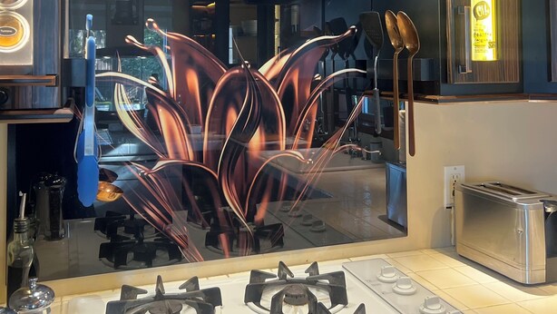 A modern kitchen with gas stoves, a decorative backsplash, and a wooden ceiling.
