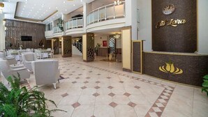 A spacious lobby with a high ceiling, multiple seating areas, and a reception desk. - Elit Lara Otel (Salihli)