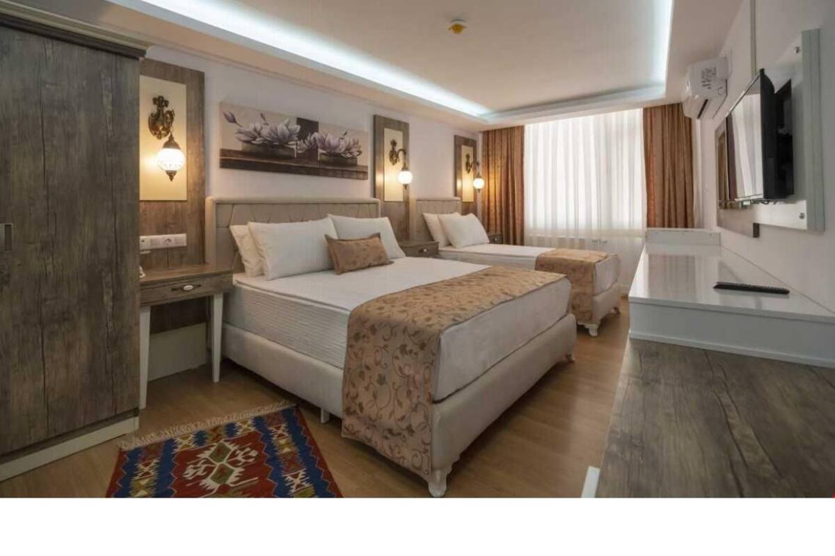 Una camera d'albergo moderna con un letto grande, una scrivania e una televisione.