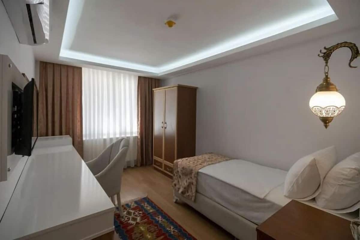 Una camera d'albergo con un letto, una scrivania, un armadio e una lampada a soffitto.