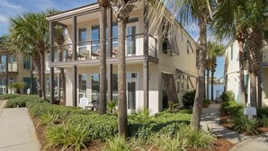 Un hotel de varios pisos con balcones, palmeras y un jardín ajardinado.