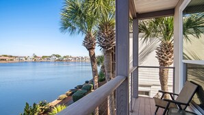 A wooden deck with a railing, overlooking a calm body of water and a row of houses. - ☀️Steps to Beach🌴Pool+Lake View | Destiny Beach Villas #9A&B☀️ (Destin)