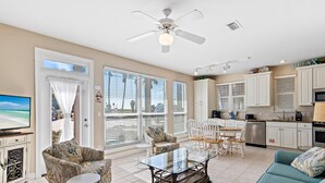 A spacious living room with a glass coffee table, a sofa, and a TV. There is a balcony with a view of the ocean. - ☀️Steps to Beach🌴Pool+Lake View | Destiny Beach Villas #9B☀️ (Destin)