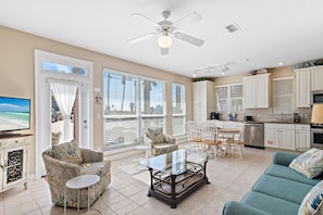 A spacious living room with a glass coffee table, a sofa, and a TV. There is a balcony with a view of the ocean. - ☀️Steps to Beach🌴Pool+Lake View | Destiny Beach Villas #9B☀️ (Destin)