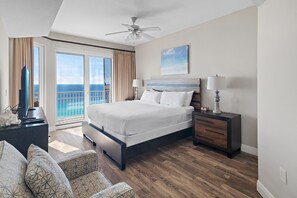 A spacious bedroom with a large bed, a nightstand, a desk, and a view of the ocean through a sliding door. - 🏝️Gulf Views | Great Amenities | Ariel Dunes I 2301🏝️ (Miramar Beach)
