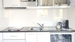 Cuina moderna amb armaris blancs, un rentamics d'acer inoxidable i un rentaplats.