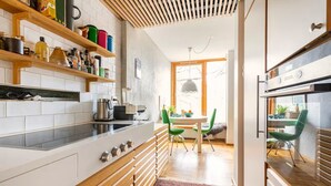 A modern kitchen with white cabinetry, wooden shelves, and a built-in oven.