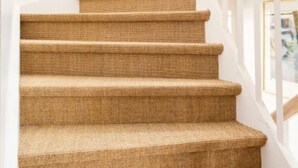 A spiral staircase with a light-colored, textured carpet.