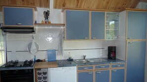 Een keuken met blauwe kastjes, een kookplaat, een vaatwasser en een koffiezetapparaat.