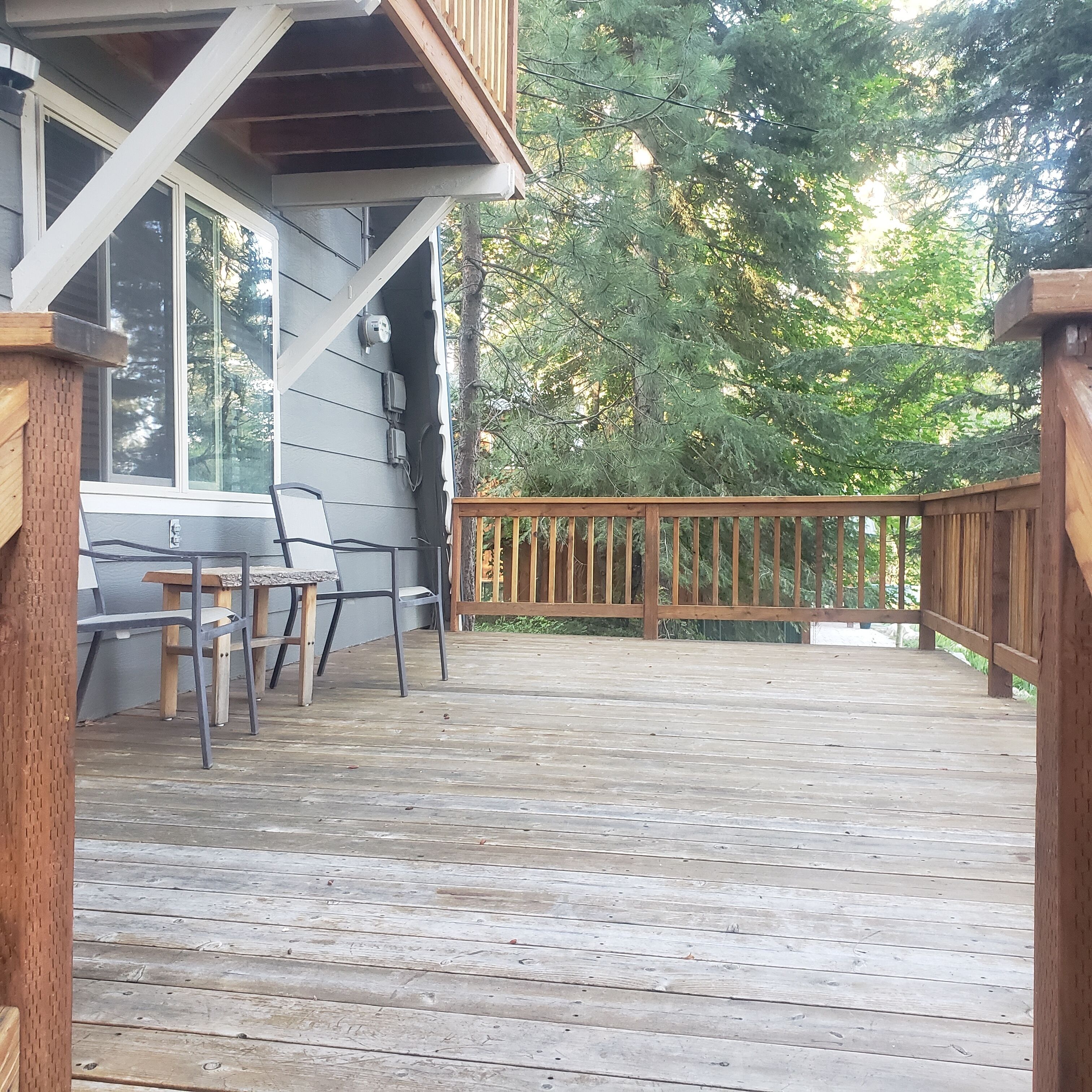 A wooden deck with a table and chairs, surrounded by trees.